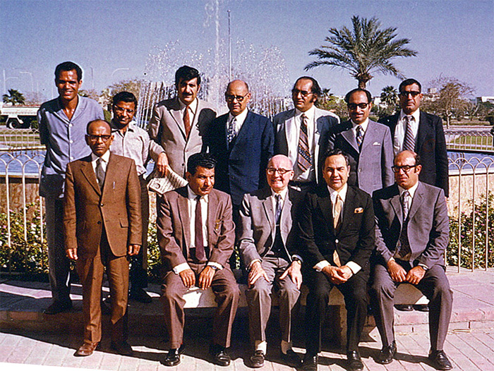 A group of men posing near a fountain in Kuwait.