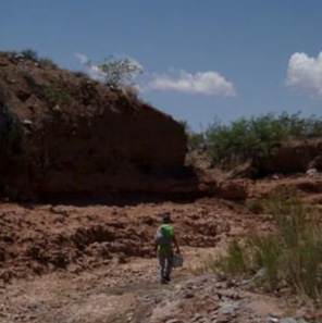 A researcher hiking in a dried river bed.
