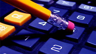 Close up image of the number keys on a calculator and the eraser end of a pencil being used to input numbers.