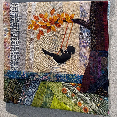 Quilt that shows a girl on a swing.