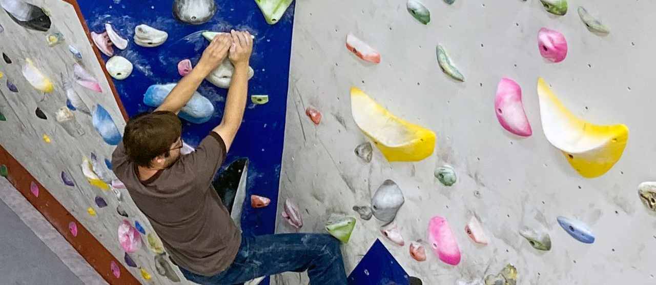 Close-up image of a male student climbing a bouldering wall